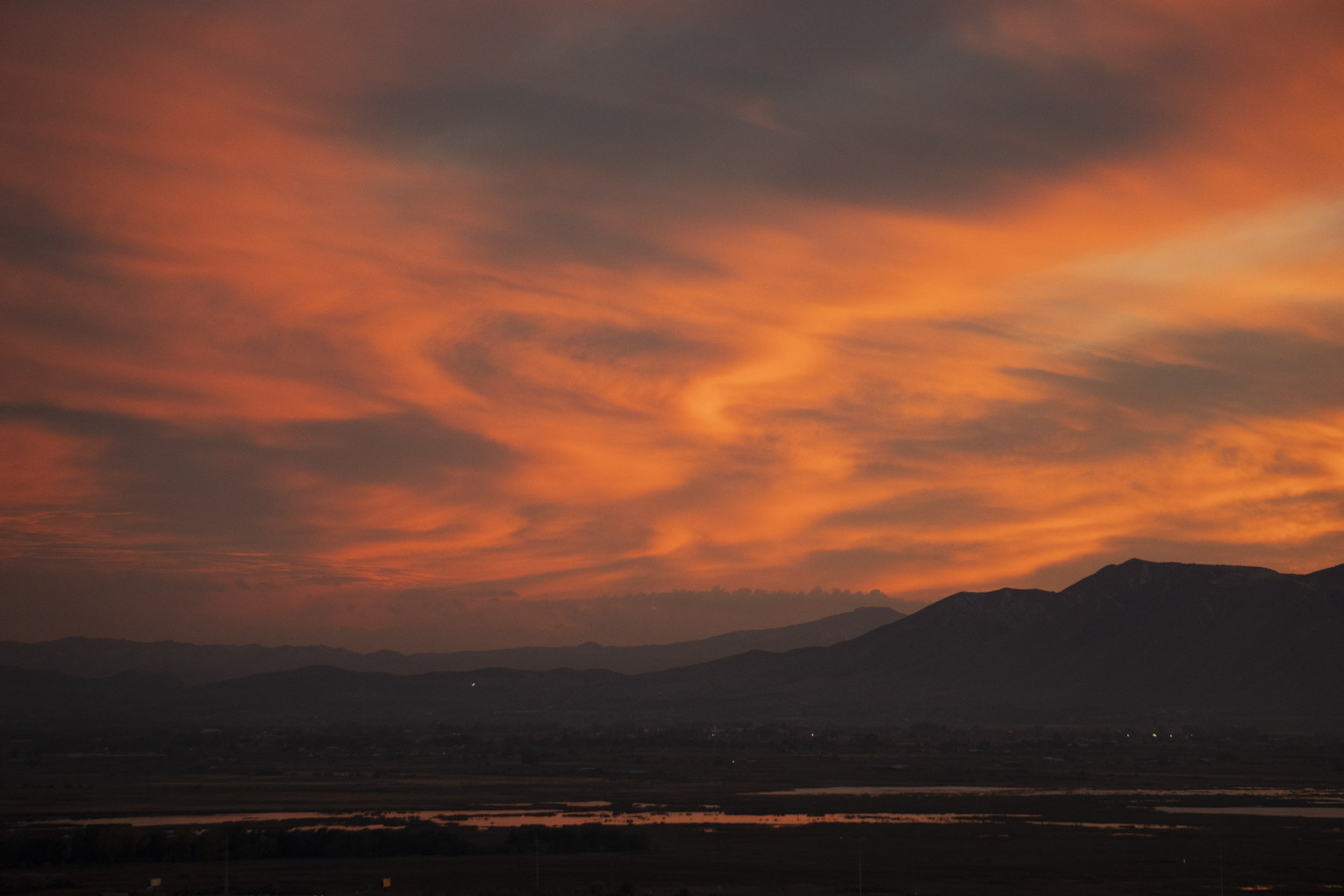 A hazy orange sunset above town and mountains